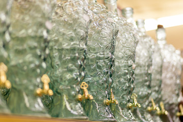 A series of figured glass bottles with faucets stand on the store shelf