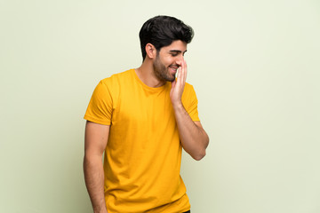 Young man over pink wall posing with arms at hip and laughing