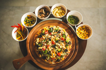 Italian fully loaded veg cheese Pizza on the table with toppings on the side