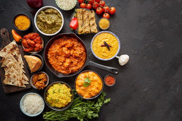 Composition of Indian cuisine in ceramic bowls on black stone table