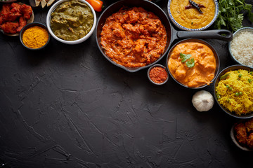 Composition of Indian cuisine in ceramic bowls on black stone table