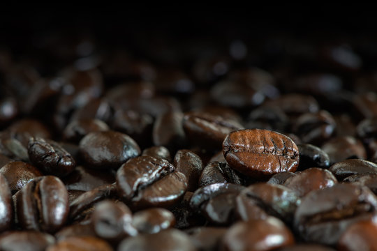 Dark brown roasted coffee beans under natural light for background © phichak