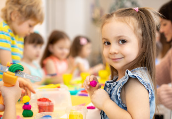 happy kids doing arts and crafts in daycare centre - obrazy, fototapety, plakaty