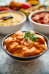 Various Indian dishes on a table. Mild butter chicken in caramic bowl