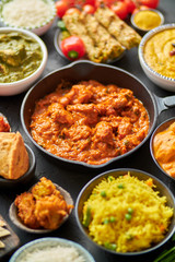 Various Indian dishes on a table. Spicy chicken Tikka Masala in iron pan