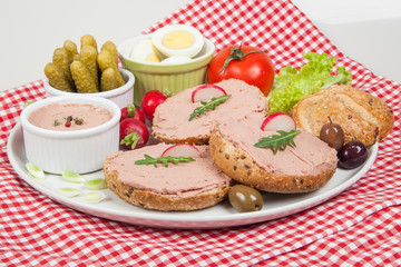Plate with slices of bread with home made pate, decorated with vegetables
