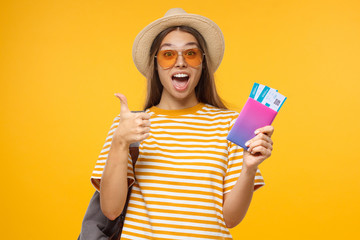 Travel concept. Young excited female student traveller showing thumbs up gesture, isolated on yellow background