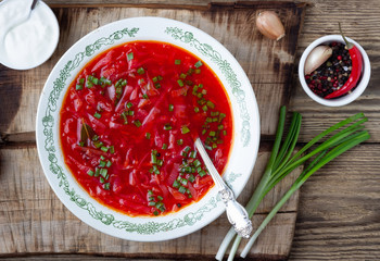 Traditional  ukrainian vegetarian beet red soup - borscht with sour cream on wooden background. Top view.