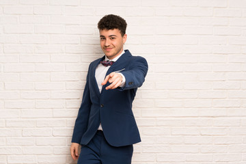 Man in suit and bow tie points finger at you with a confident expression