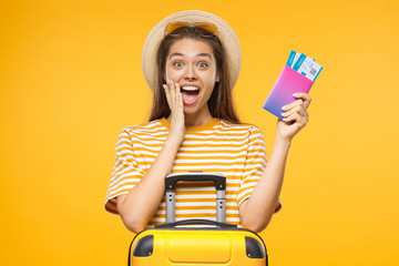 Excited screaming WOW young woman tourist holding passport with tickets and suitcase, isolated on...