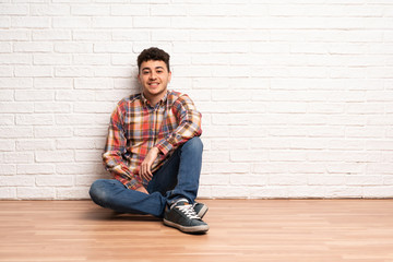 Young man sitting on the floor keeping the arms crossed in frontal position