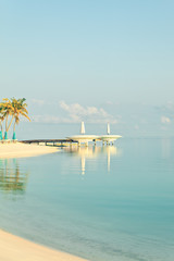 Vertical composition of morning sea side view at small peer and white umbrellas