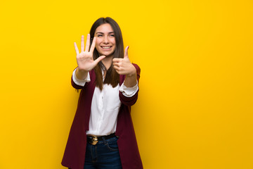 Fototapeta na wymiar Young woman over yellow wall counting six with fingers