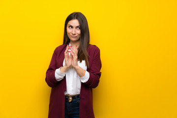 Young woman over yellow wall scheming something