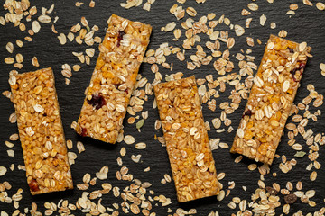 Granola bar. Healthy sweet dessert snack. Cereal granola bar with nuts, fruit and berries on a black stone table. Top view.
