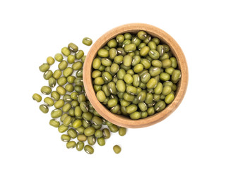 Mung beans in a small wooden bowl with pile next to it seen directly from above and isolated on white background