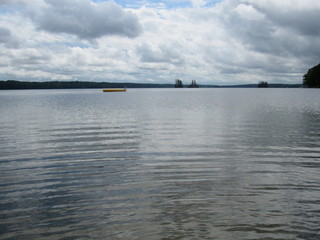 Beautiful view of Damariscotta Lake in Maine with a yellow floating raft and islands in the background on a cloudy day