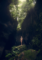 Waterfall Tukad Cepung. Waterfall in Bali. The gorge. A girl in a bathing suit at the waterfall Travel.
