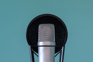 Professional studio microphone with pop filter and shock absorber on a blue background. The concept of high-quality sound and voice recording. Close-up. Copy space.