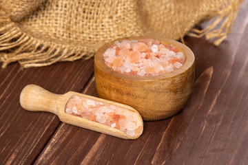 Lot of pieces of mineral pink himalayan salt crystals in a scoop on brown wood