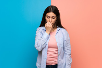 Young woman over pink and blue wall having doubts