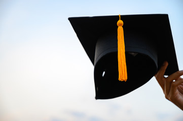 The arms of the graduates holding a black hat extended forward.