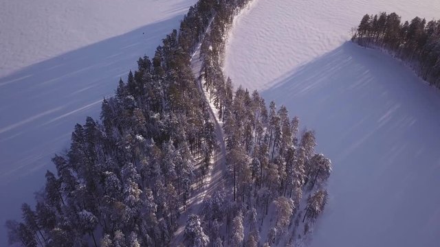 Car driving on scenic ridge road in middle of frozen lake
