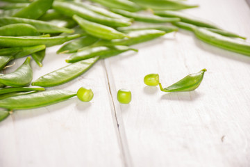 Lot of whole fresh green sugar snap pea on white wood