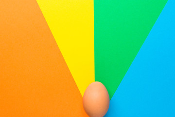 One brown Easter egg on multicolored pinwheel ray burst background in retro 60s aesthetics. Creative holiday poster card. Kids style. Graphic mockup collage template with copy space