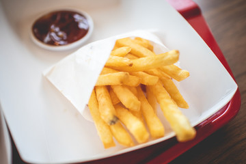 French Fries in the paper bag with tomato sauce served in the franchise cafe.