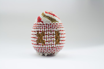 One Easter egg made from beads on a white background