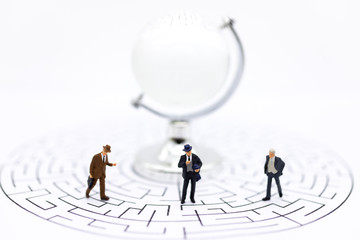 Miniature people : Businessmen standing on maze map and looking for a solution with teamwork. Image use for solve problems and new idea concept.