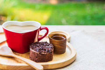 Coffee  in the red cup and chocolate cake  for breakfast in the garden.