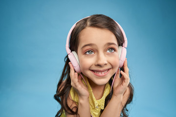 Close up of little girl in pink headphones smiling..