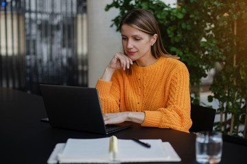 Portrait of smiling woman sitting and using laptop in co-working, business woman working on laptop...