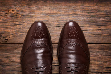 Men's shoes on the wooden floor top view. A pair of men shoes close-up on a wooden background.