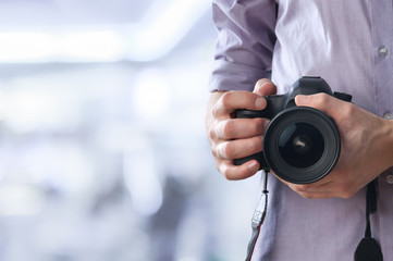 Fototapeta premium Young man holds modern digital black camera