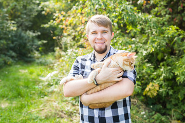 people, summer tourism and animals concept - handsome young man with cute cat outdoors