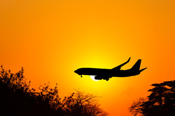 Silhouette airplane flying on sunset and prepare for landing.