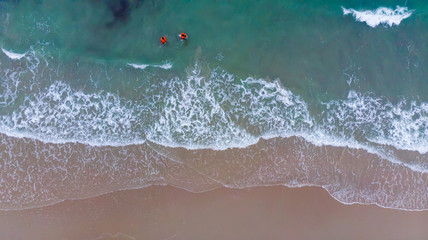 Aerial view tropical beach with group of people playing in turquoise ocean water and waves, Top view Soft wave of emerald clear sea of paradise island