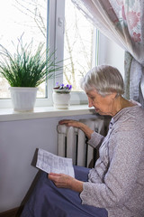 Woman holding cash in front of heating radiator. Payment for heating in winter. Selective focus.