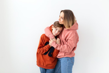 Mothers day, children and family concept - teen boy hugging his mom on white background
