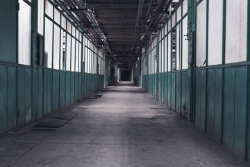 Long corridor of an old factory stretching into darkness. Concept of obscurity