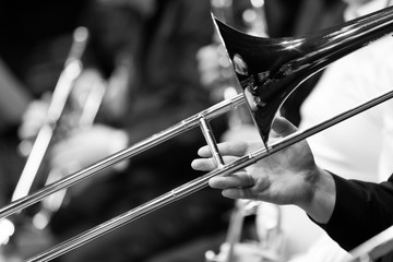 Hand of man playing the trombone in black and white