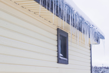 Icicles hang from the roof of a private house in winter