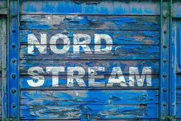 An old, poorly painted and partially peeled wooden surface of blue color with an inscription NORD...