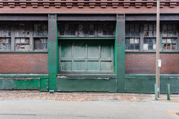 Back of a vintage industrial red brick factory with large green loading dock