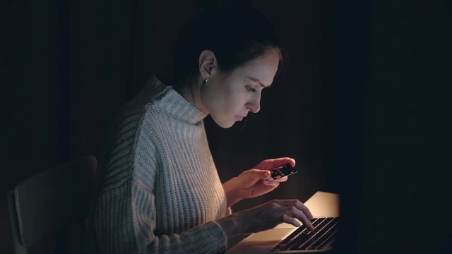Beautiful caucasian woman using laptop buying online shopping by credit card sitting at desk in living room in the night at home. slowmotion.