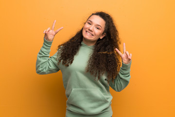 Teenager girl over ocher wall showing victory sign with both hands