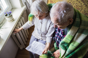 Woman holding cash in front of heating radiator. Payment for heating in winter. Selective focus.